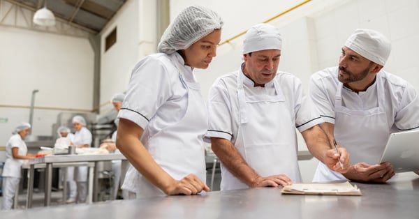 Three employees discussing something, in a food manufacturing factory