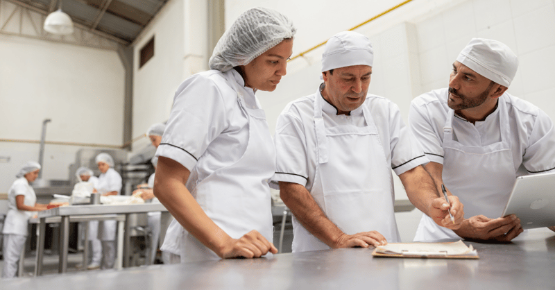 Three employees discussing something, in a food manufacturing factory