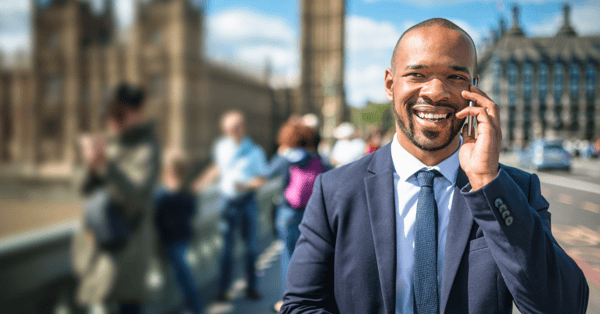 Black, male employee wearing a suit, taking a phone call while walking through London